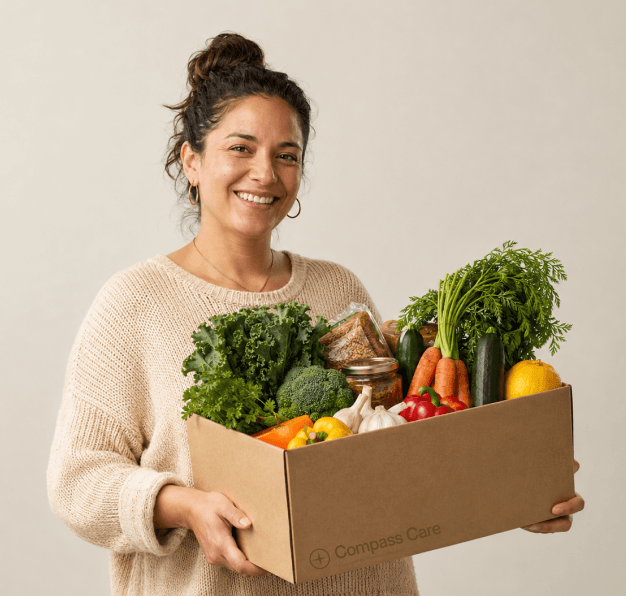Woman carrying a cardboard box full of organic fresh vegetables